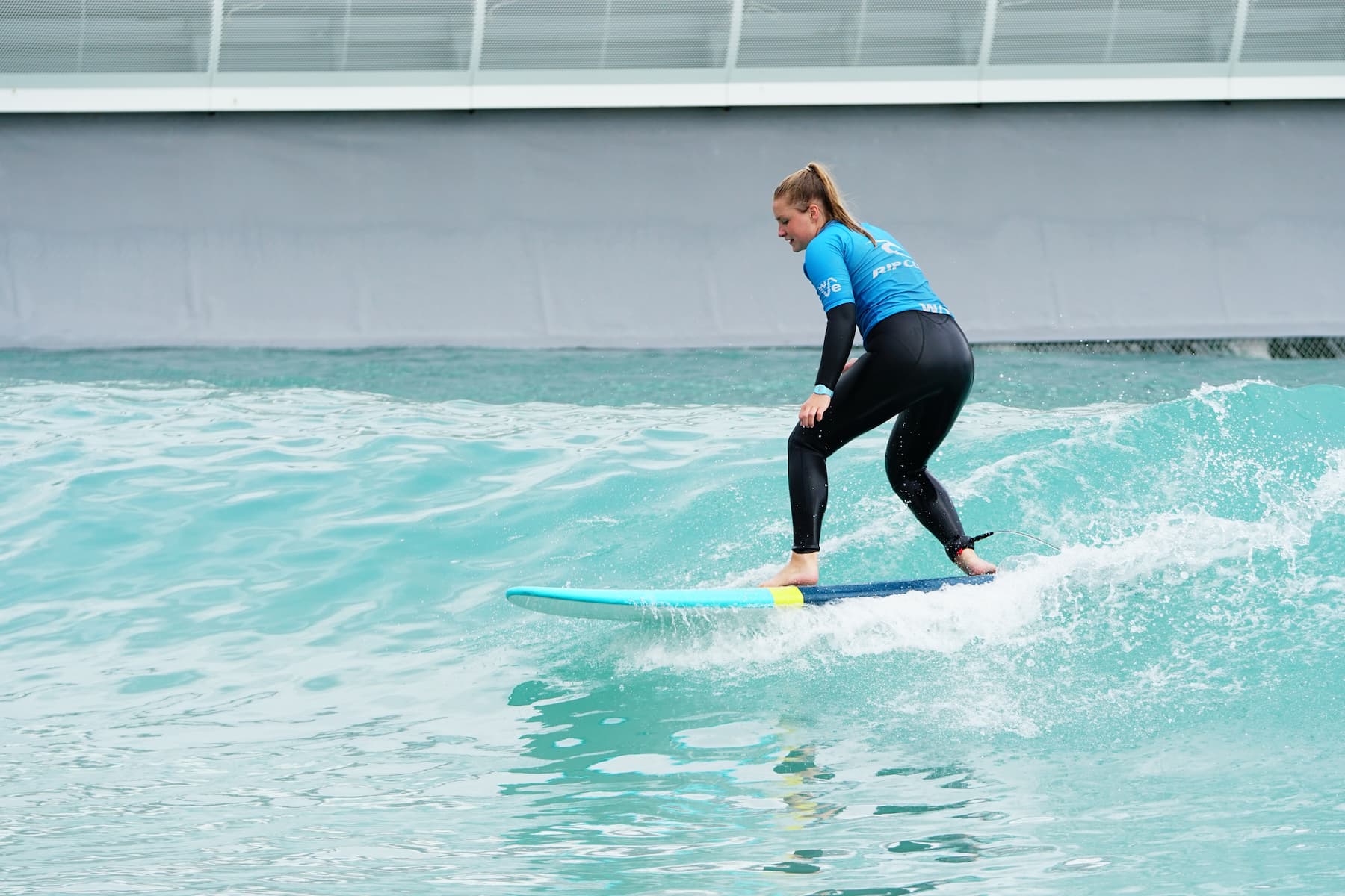 Woman surfs intermediate wave at inland surf lake The Wave near Bristol