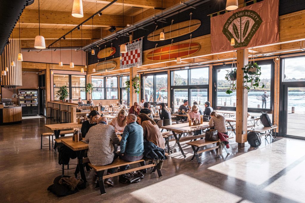 Inside the restaurant at The Wave with various groups of people sitting down and speaking
