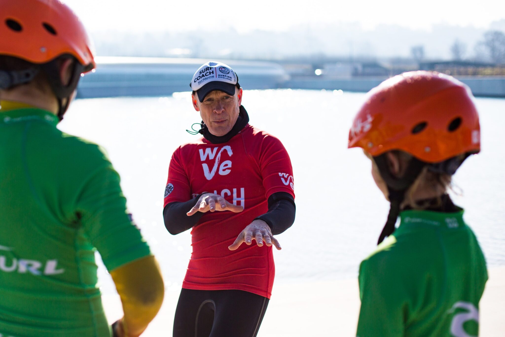 Surf coach explaining how to catch a wave to two kids at The Wave near Bristol