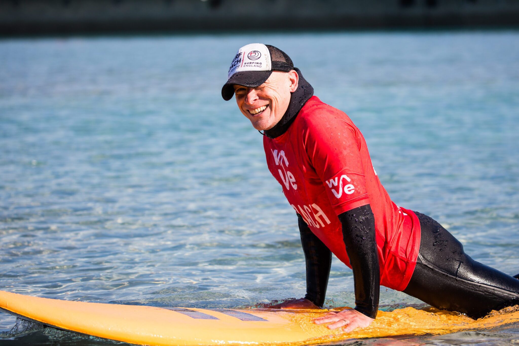 Surf coach smiling on top of a board at inland surfing lake The Wave in Bristol
