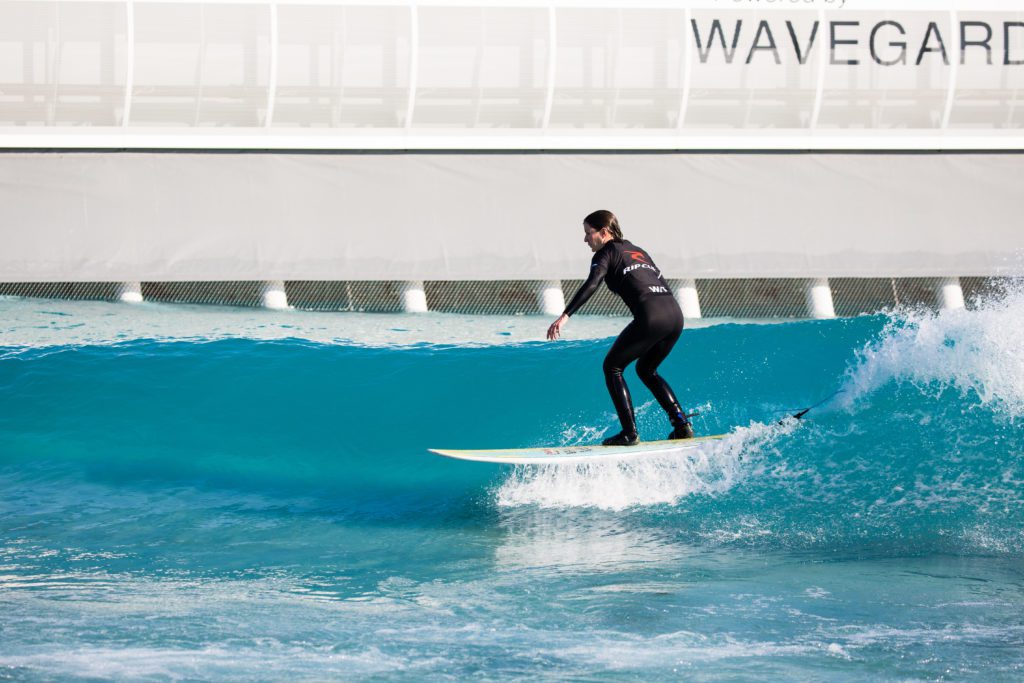 Surfer riding green waves at The Wave, inland surfing lake powered by Wavegarden in Bristol