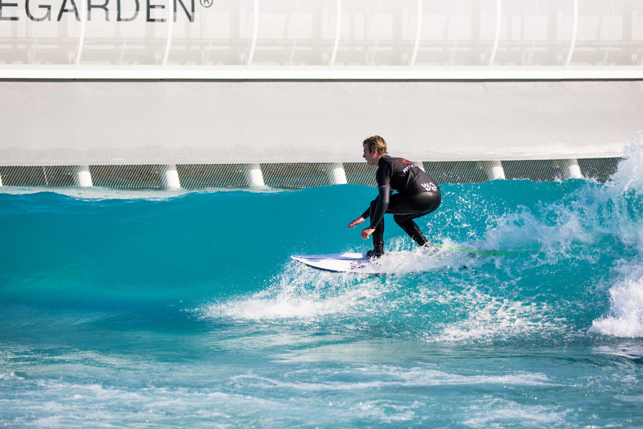 Surfer riding green waves at the inland surfing lake of The Wave in Bristol