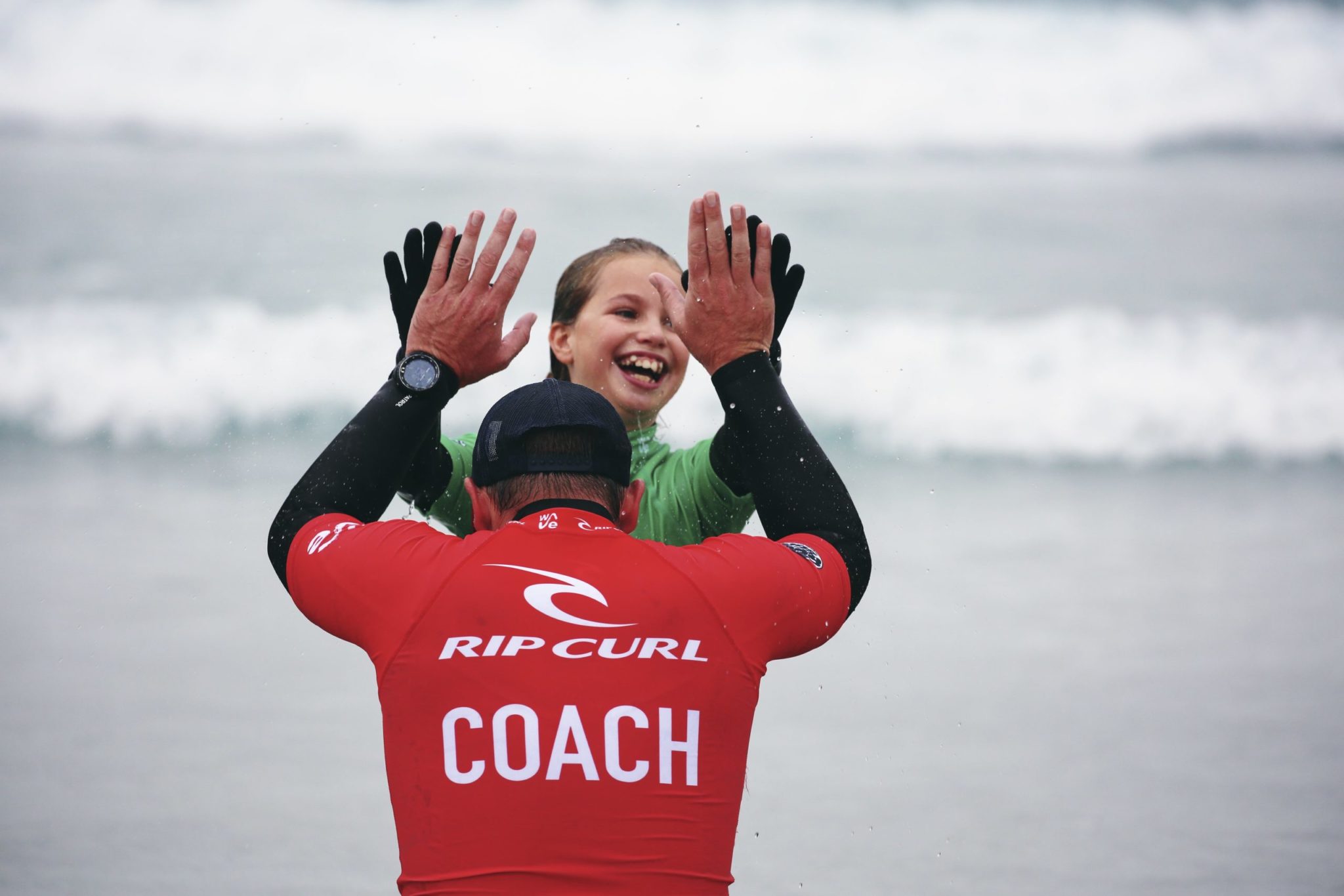 Girl high fives surf coach during beginner surf lesson at The Wave inland surf lake near Bristol
