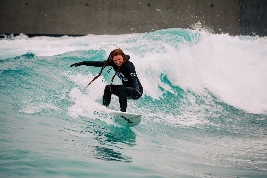 Woman smiling surfing during winter at The Wave in Bristol