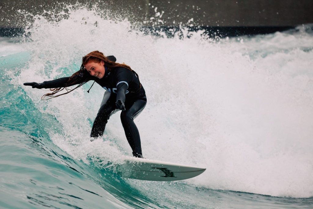 Woman having fun surfing during winter at The Wave, surfing inland lake in Bristol