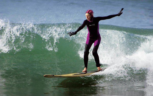 Old woman surfing in wetsuit
