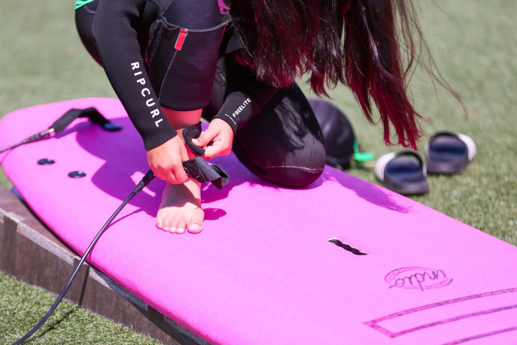 Woman surfer attaching surf leash to ankle