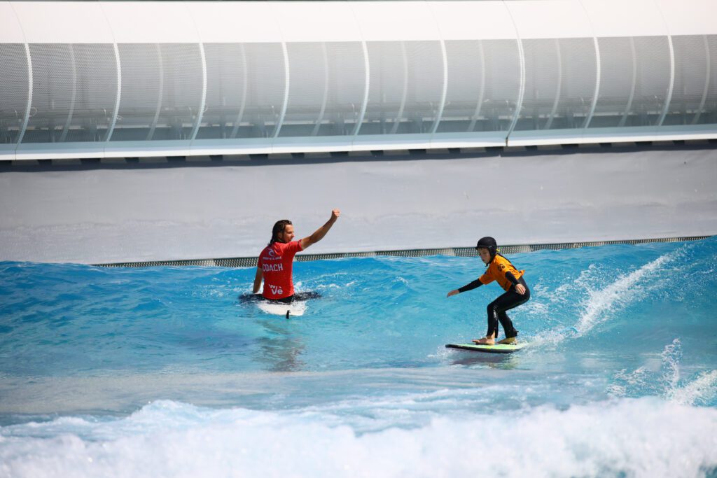 A child surfs with a coach in a Little Improvers Surf Lesson at The Wave Bristol