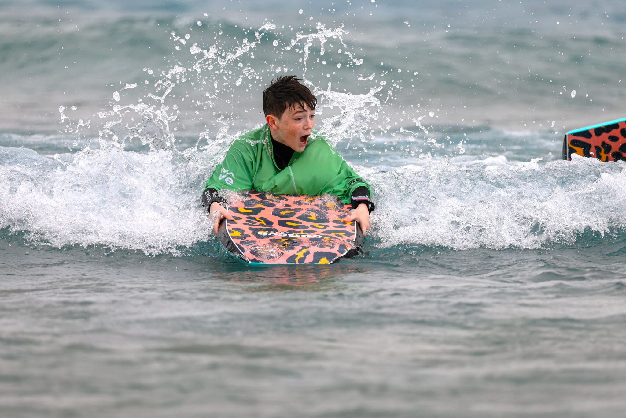 A young boy rides a bodyboard at a Play in the Bay session at The Wave