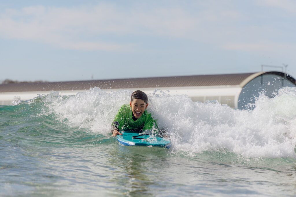 A young boy rides a bodyboard during a Play in the Bay session.