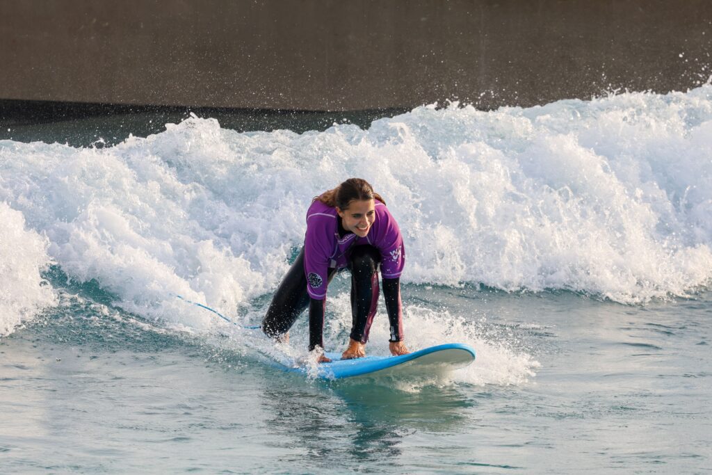 Women surfing on the waikiki wave at The Wave inland surf lake near Bristol