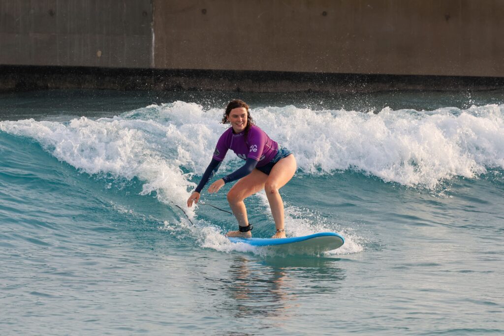 A woman rides the Improver wave in a surf session at The Wave Bristol.