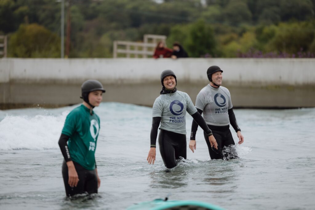 A group of volunteer coaches from The Wave Project help young people in the waves.