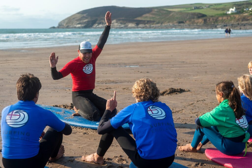Surf coach on the beach giving a surfing lesson.